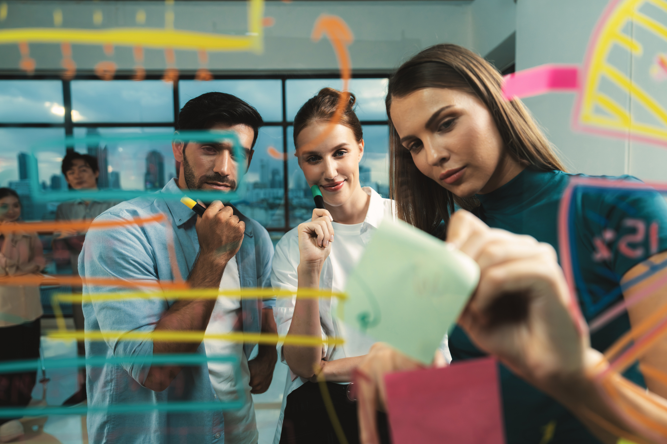 Skilled project manager pointing at glass wall while coworker thinking about plan. Diverse business team working together, brainstorming marketing idea or business plan. Creative start up. Tracery.