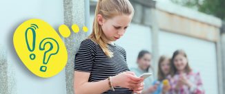 Young girl looks pensively at her phone with other girls in the background. Yellow thought bubble with an exclaimation point and a question mark.