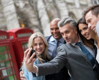 Group of business people taking a selfie outdoors with a smart phone