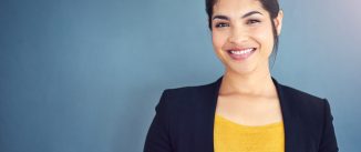 Cropped studio portrait of a young businesswoman standing against a gray background