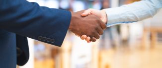 Mid section close-up of diverse Business people shaking hands with each other in corridor at office. International diverse corporate business partnership concept