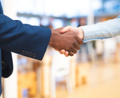 Mid section close-up of diverse Business people shaking hands with each other in corridor at office. International diverse corporate business partnership concept