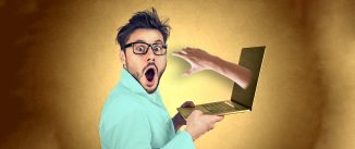 A shocked man holding a laptop open with a hand reaching out of the screen.