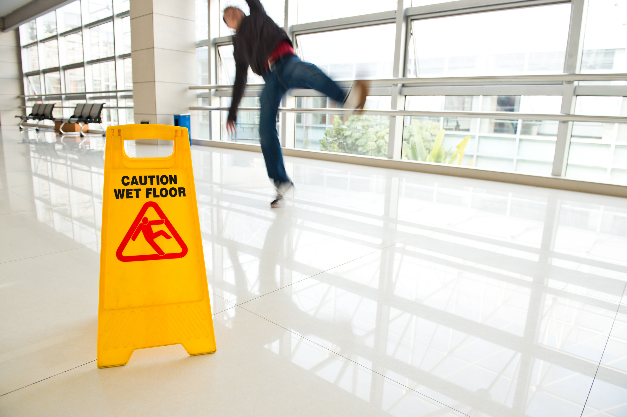 Man slips falling on wet floor next to the wet floor caution sign.