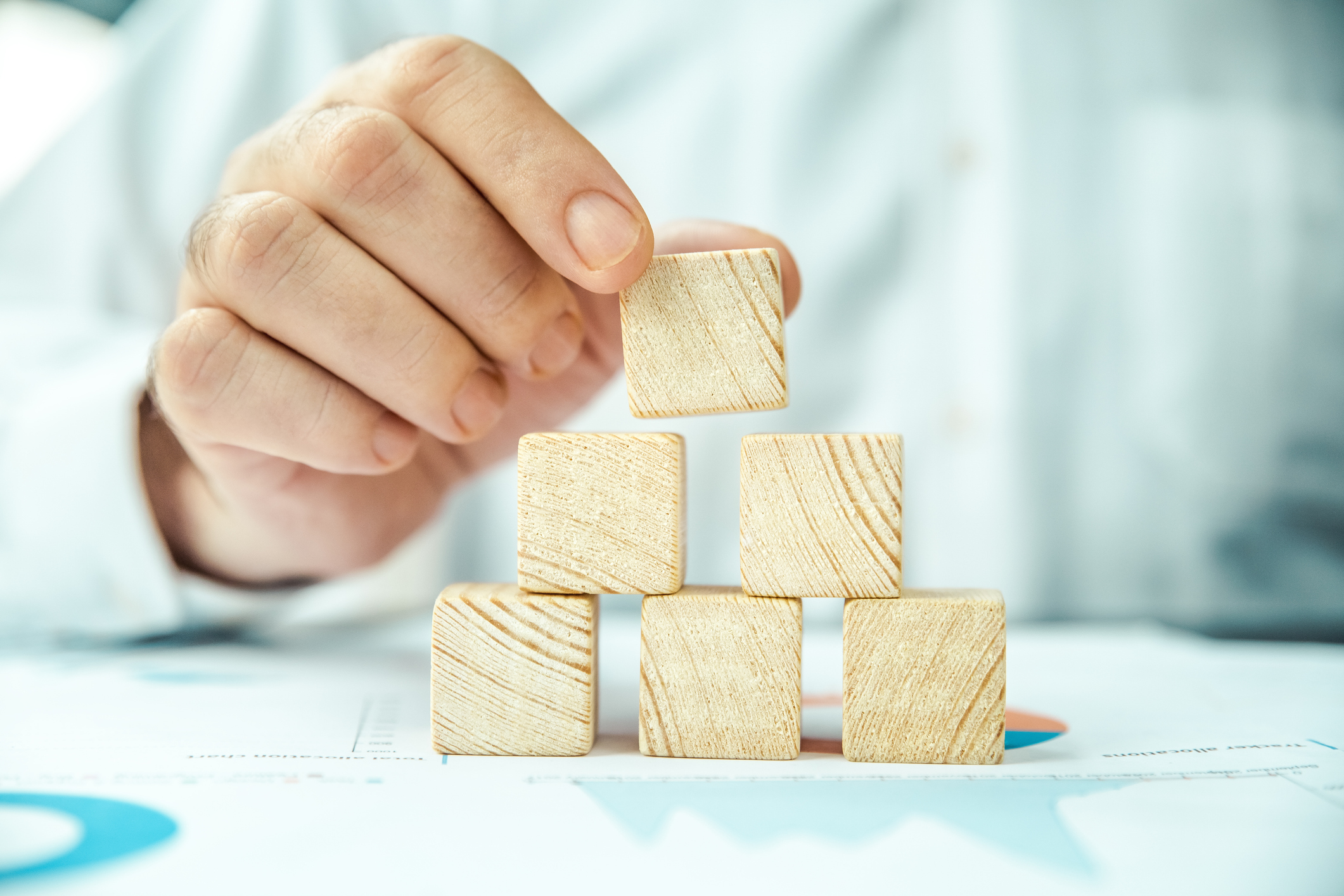 Closeup of a man's hand stacking wooden blocks in a pyramid