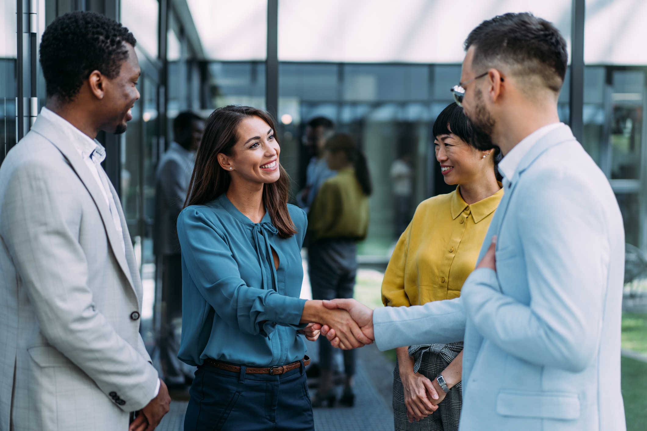 Businesspeople handshaking in front of modern office building.