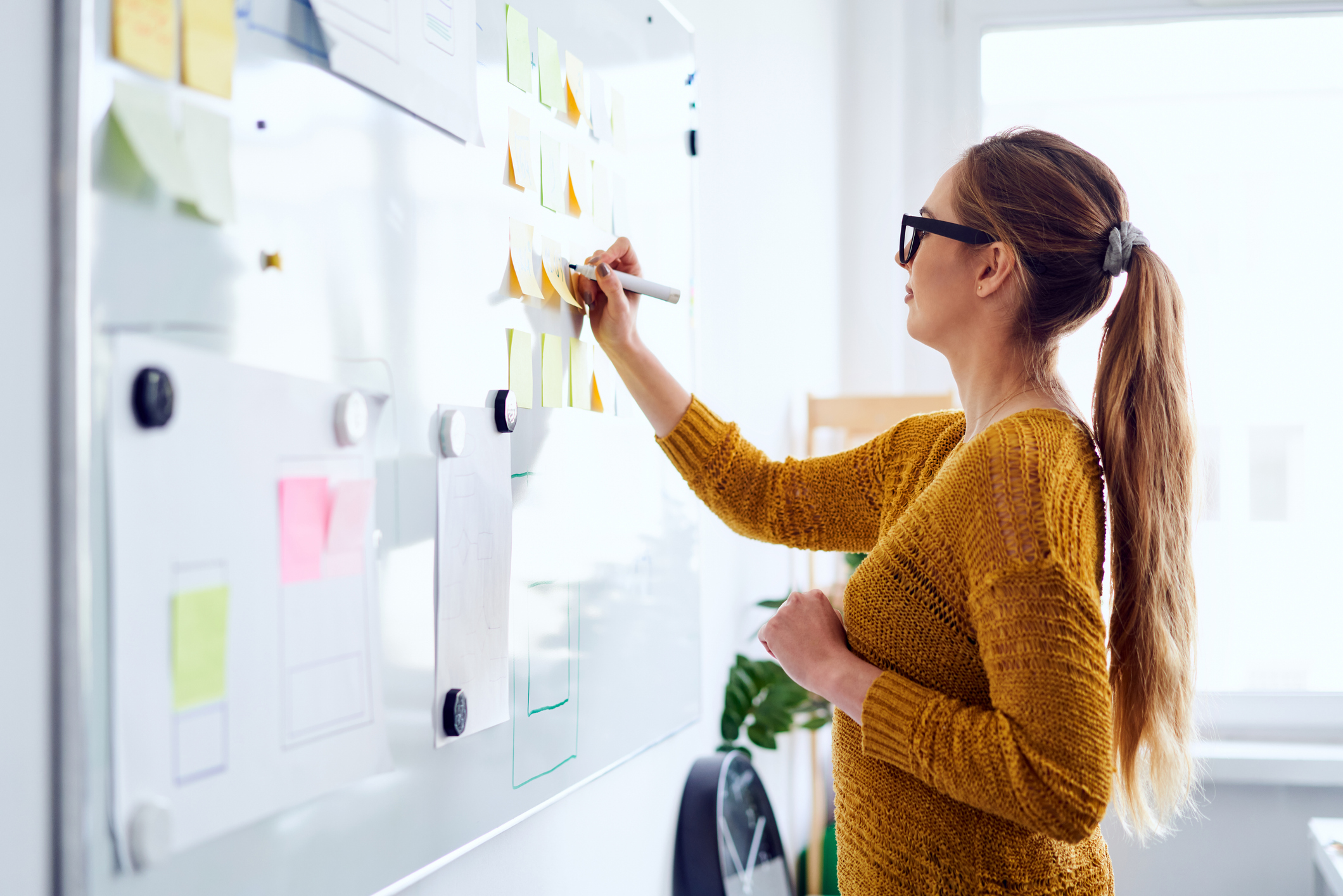 Young woman working in startup office writing on whiteboard