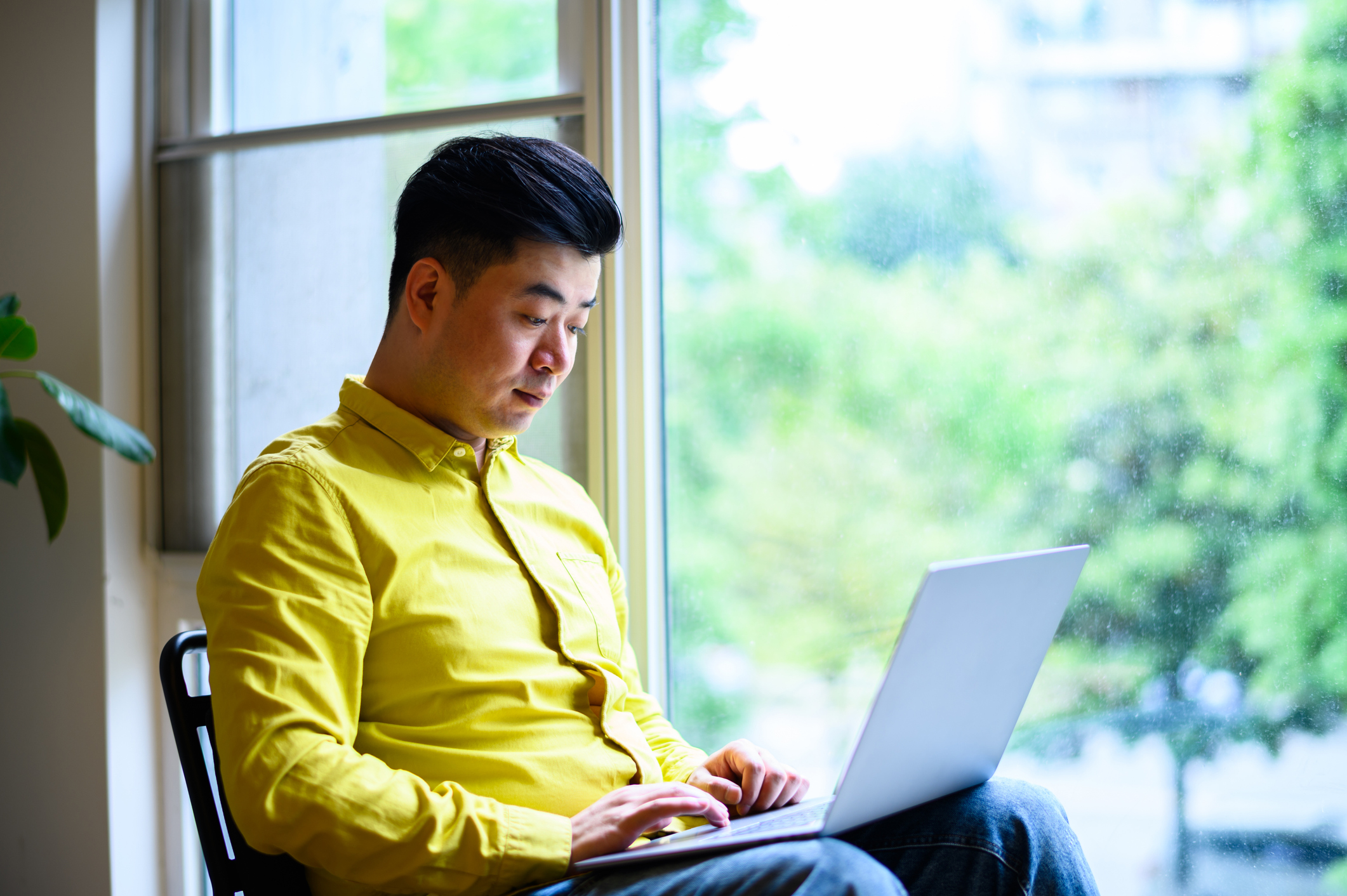 Asian young man at home on his laptop