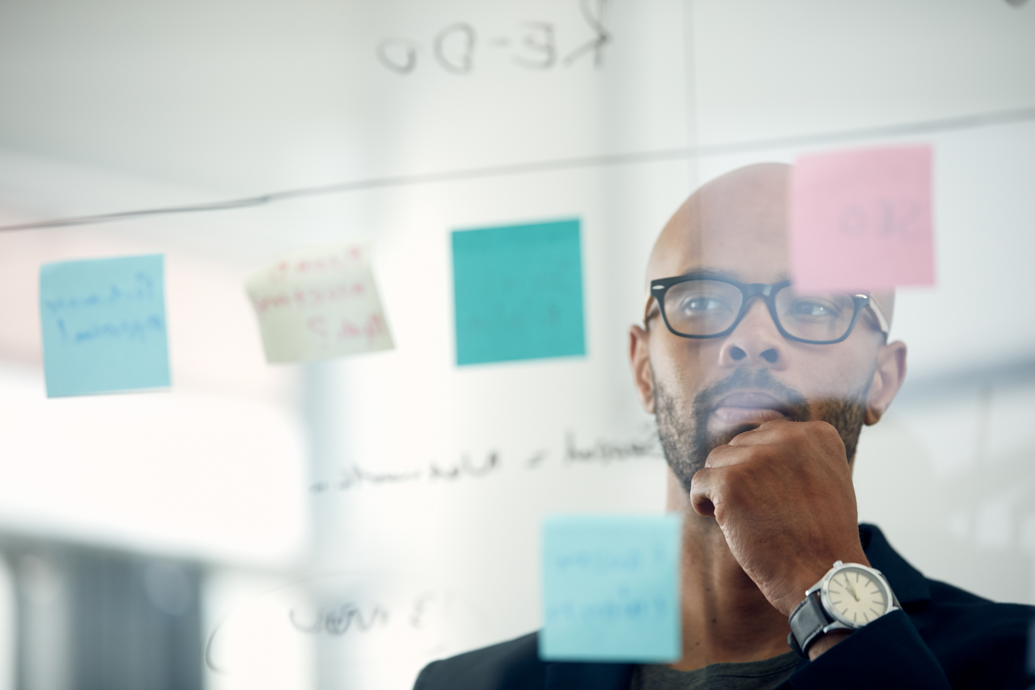 Cropped shot of a young businessman brainstorming with notes on a glass wall in an office