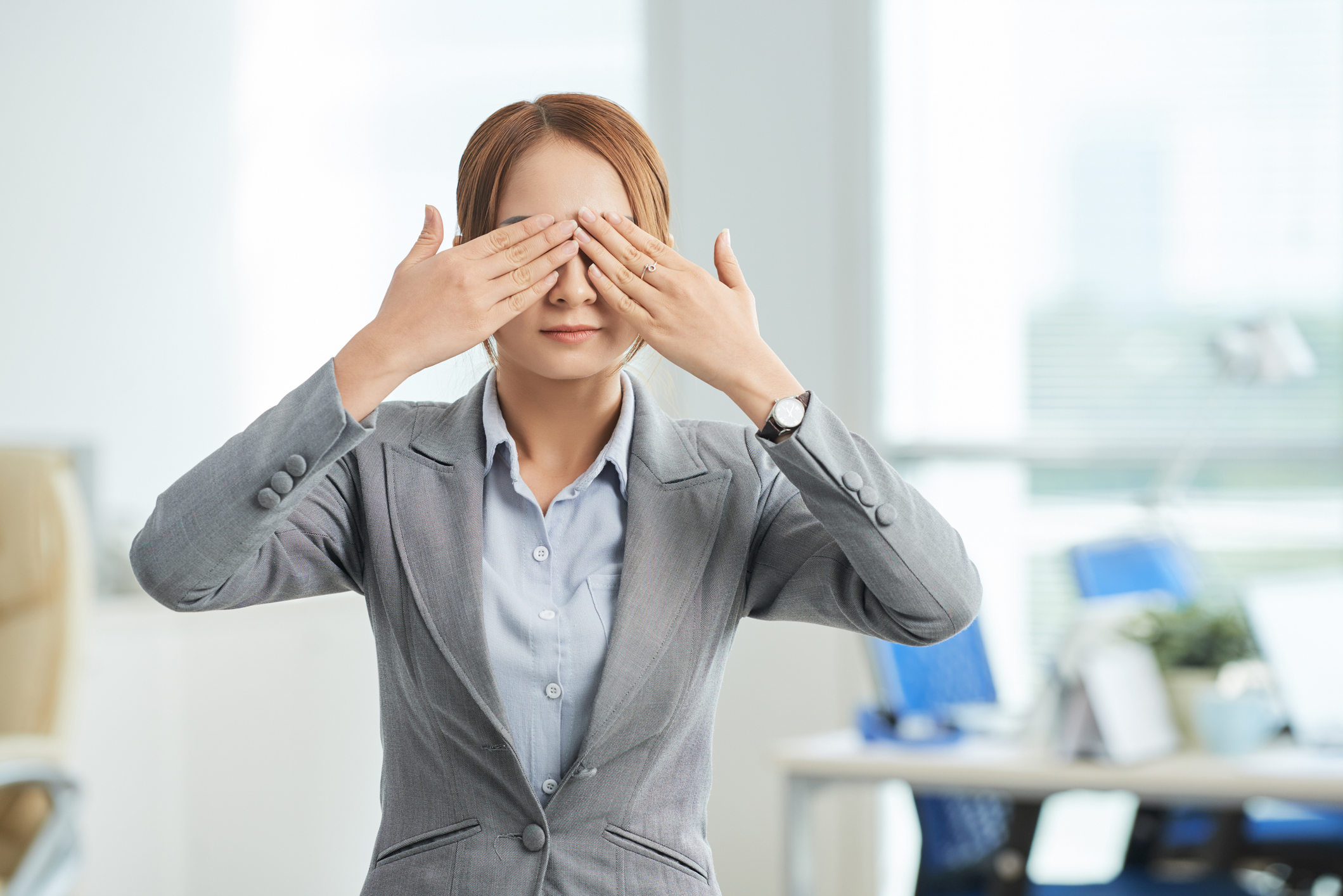 Young businesswoman covering her eyes with her hands