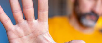 Man with yellow t-shirt showing palm hand in stop gesture.