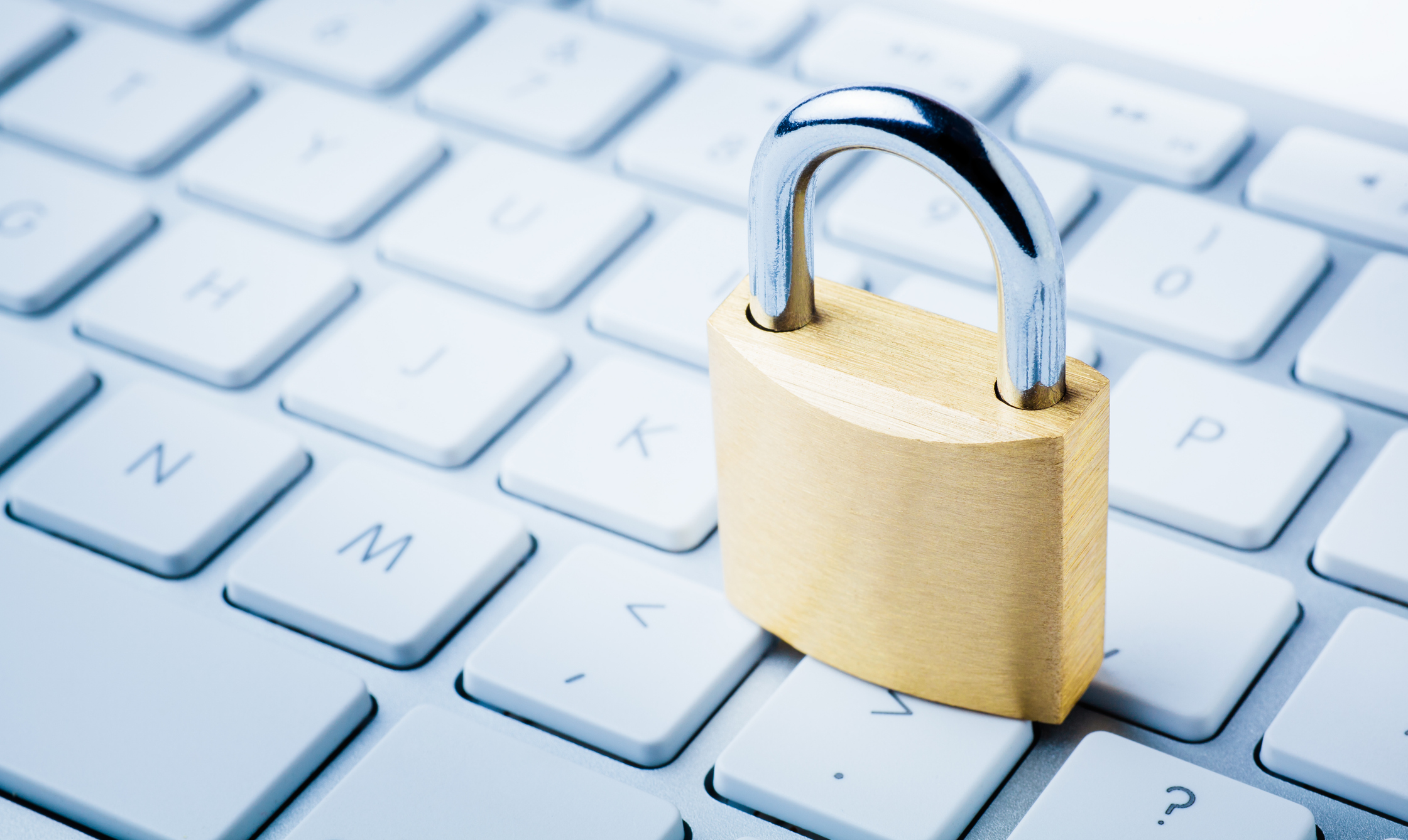 A gold padlock sitting on top of a gray computer keyboard