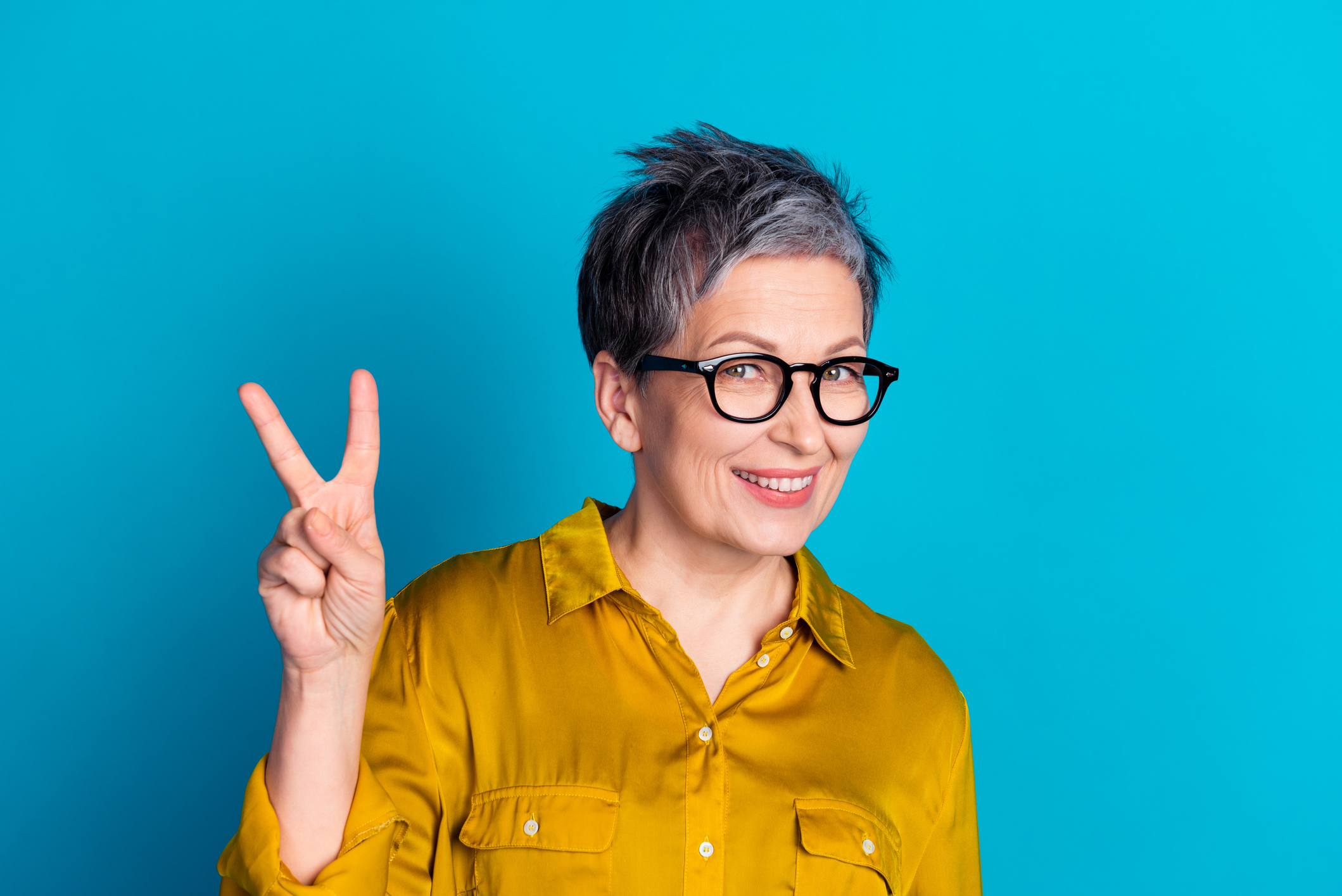 Photo of pretty cheerful woman wear blouse spectacles showing v-sign emtpy space isolated blue color background.